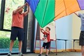 Parents and kids with a storytime parachute in the air.