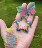 three shrinky dinks on the palm of a hand.