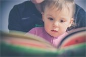 Baby looking at an open book.