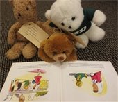 Three stuffed animals reading a book.